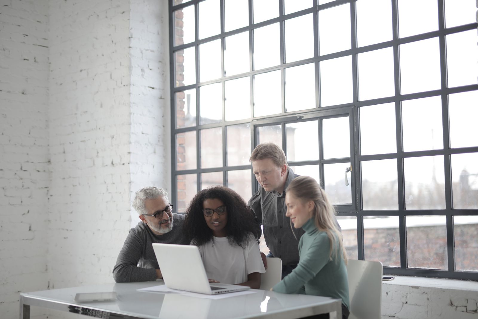 Colleagues of different ages working together around a laptop